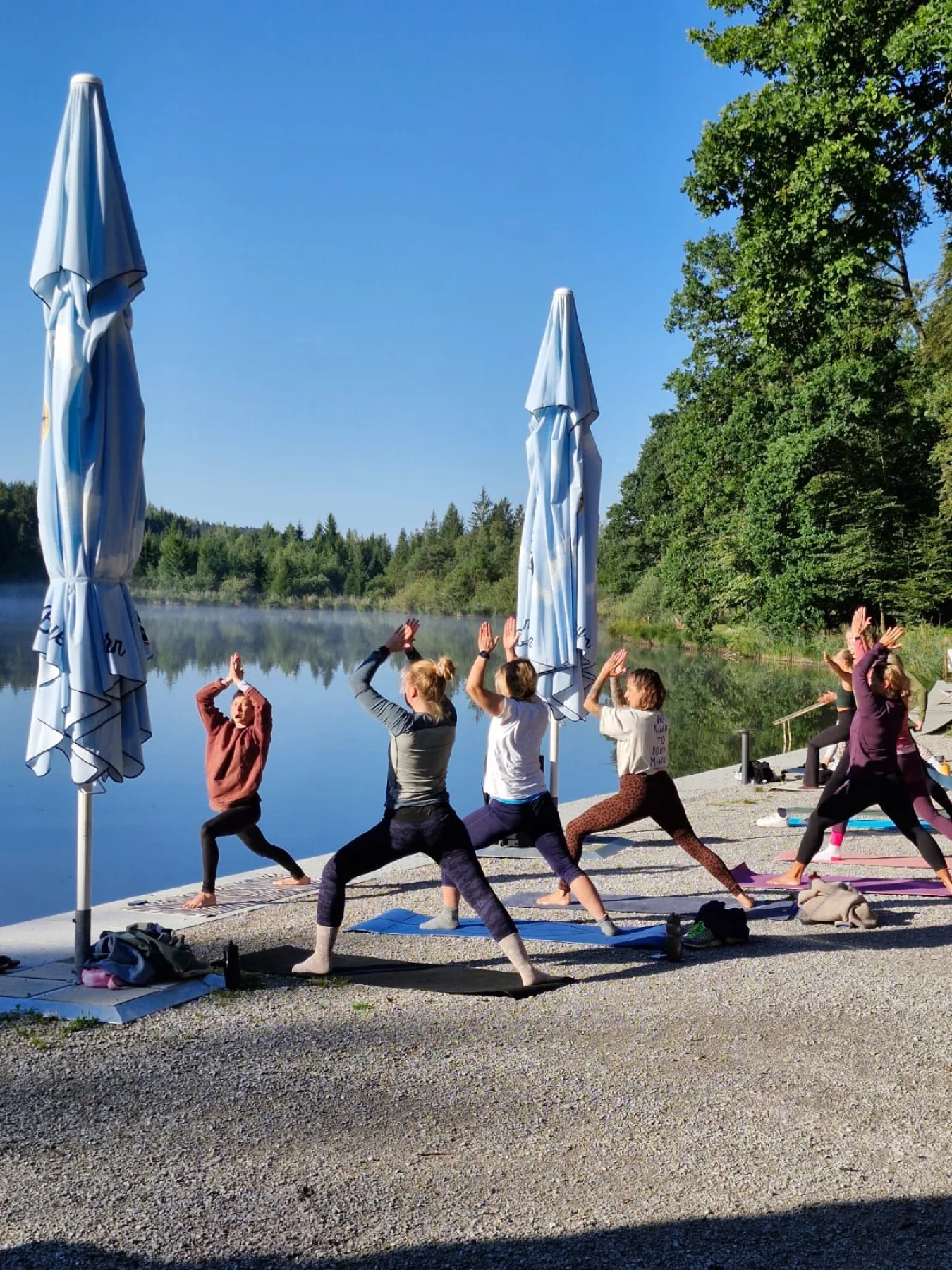 Frauen machen gemeinsam Yoga an einem ruhigen See